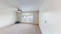 Located at 1509 30th St SE in Auburn, Washington, this single-floor unit offers a practical and straightforward layout designed for comfortable everyday living. The living area is generously proportioned, featuring soft wall-to-wall carpeting, neutral-toned walls, and a ceiling fan with integrated lighting. A large picture window allows natural light to fill the space while offering views of the surrounding neighborhood. Baseboard heating runs along the perimeter, providing consistent warmth throughout. The textured ceiling adds a classic architectural detail consistent throughout the unit.

The kitchen is efficiently designed with white cabinetry extending to the ceiling, offering ample storage. A double-basin sink, electric range with overhead ventilation, and a full-size refrigerator complete the appliance lineup. Light-toned countertops and wood-style flooring give the kitchen a clean, functional aesthetic. A peninsula-style breakfast bar separates the kitchen from the adjacent carpeted living space, creating a natural flow between areas.

The bathroom features wood-style flooring, a vanity with a single sink, and a full tub-shower combination. Louvered bifold doors provide access to a closet with built-in shelving, conveniently positioned adjacent to the bathroom for added storage functionality.