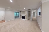 This single-floor residence offers a thoughtfully designed layout that balances open living spaces with comfortable private areas. The expansive main living room serves as the centerpiece of the home, featuring plush wall-to-wall carpeting, elegant crown molding, recessed lighting, and a classic white-mantled fireplace flanked by built-in shelving units — ideal for display or storage. A large window invites natural light and provides views of lush greenery outside, enhancing the room's warm and inviting ambiance. The kitchen is efficiently laid out with white cabinetry, light countertops, stainless steel appliances including a gas range and refrigerator, a double-basin sink, and tile flooring. A louvered door leads to an adjacent pantry or storage closet, adding practical convenience. The bedrooms are carpeted and well-proportioned, with one featuring a ceiling fan and a window overlooking outdoor greenery, contributing to a bright and airy feel. The bathrooms are clean and functional, each equipped with a single-sink vanity with white cabinetry, a tub-shower combination with tile surround, and tile flooring. Throughout the space, neutral tones create a cohesive and versatile aesthetic suitable for a variety of furnishing styles.