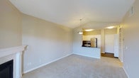 Located at 10500 Irma Drive in Northglenn, Colorado, this single-floor residence offers a clean and functional open-concept design. The living area is spacious and inviting, finished with plush wall-to-wall carpeting and neutral-toned walls that create a bright, airy atmosphere. Vaulted ceilings add a sense of vertical openness, enhancing the overall feeling of the space.

The kitchen is seamlessly integrated into the living area via a peninsula-style breakfast bar with a dark countertop, providing both a natural visual divider and a convenient surface for dining or casual seating. The kitchen is outfitted with white cabinetry, a stainless steel refrigerator, and a stainless steel sink, giving it a modern and practical character. A stylish pendant light hangs above the peninsula, adding a focal point to the shared living and kitchen space.

Additional recessed and overhead lighting ensures the interior remains well-lit throughout. The entry area, visible from the main living space, features a white door and hardwood-style flooring, offering a smooth transition between spaces. The overall design is simple yet thoughtful, making this a comfortable and move-in-ready residence in the Northglenn community.