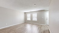 Located at 1707 Meadowlark Ct in Kansas City, Kansas, this two-story home offers a clean, modern aesthetic throughout its well-appointed layout. The main level features durable luxury vinyl plank flooring in a warm, light wood tone that flows through the living areas and kitchen. The kitchen is a standout space, designed in a galley style with crisp white shaker cabinetry, granite countertops, a subway tile backsplash, stainless steel appliances including a range, microwave, and refrigerator, and a deep undermount sink. A half bathroom on the main level includes a white shaker vanity with granite countertop, a light fixture above the mirror, and wood-look flooring. The upper level hosts multiple carpeted bedrooms, each finished with neutral wall tones and window blinds that allow natural light. The primary bedroom features vaulted ceilings, a ceiling fan, and a walk-in closet, while additional bedrooms include closets and windows with exterior views. A full bathroom on the upper level is equipped with a tub-shower combination with white tile surround. Textured ceilings are present throughout the main level, and clean white baseboards and trim provide a polished finish across both floors.