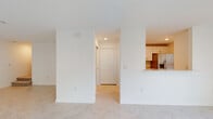 Located at 2101 E Landings Way in Port Charlotte, Florida, this two-story residence offers a clean, modern design characterized by a light and airy aesthetic throughout. The main living area features large-format light tile flooring that reflects natural light streaming in through sizable windows dressed with horizontal blinds, creating a bright and welcoming atmosphere. The kitchen is designed with a pass-through counter opening into the living space, white cabinetry, and stainless steel appliances, making it both functional and connected to the main living area. A hallway with a double-door closet provides practical storage and leads to additional rooms. The bedrooms are finished with plush neutral carpeting and windows that allow for natural light. Multiple bathrooms serve the home, including one featuring a walk-in shower with a framed glass door and a marble-look countertop vanity, and another with a full tiled tub-surround, toilet, and matching vanity. Throughout, the interiors are finished in crisp white tones with clean lines and recessed lighting, lending a fresh and move-in-ready feel. The overall ambiance is bright, clean, and functional, well-suited to the warm Florida climate.