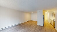 Located at 19605 SW Boones Ferry Rd in Tualatin, Oregon, this single-floor unit offers a clean, functional layout with thoughtfully updated finishes throughout. The open living area features wood-style plank flooring, crisp white walls, a textured ceiling, and baseboard heating running along the perimeter. A large window with vertical blinds allows natural light to fill the space and provides a view of the surrounding exterior. The living area flows toward the kitchen, which is outfitted with gray shaker-style cabinetry, white countertops, a stainless steel undermount sink with a contemporary pull-down faucet, and a dishwasher — offering a modern and practical cooking environment. The bedroom is carpeted in a neutral gray tone and includes a ceiling fan, a baseboard heater, and a window with vertical blinds that brings in additional natural light. The bathroom is finished in a bright, all-white palette with wood-style flooring, a tub-shower combination, a white vanity with brushed gold hardware, and a wall-mounted mirror. Throughout the unit, the consistent use of neutral tones and updated fixtures creates a cohesive, move-in-ready living environment well-suited for everyday comfort.