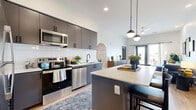 Located at 139 N Dobson Rd in Mesa, AZ, this well-appointed 2-bedroom, 2-bathroom residence offers a thoughtfully designed single-level layout with modern finishes throughout. The open-concept kitchen and living area serves as the heart of the home, showcasing sleek gray cabinetry extending to the ceiling, a white subway tile backsplash, stainless steel appliances, and a large quartz-topped island with bar seating — ideal for both cooking and casual dining. Stylish globe pendant lights illuminate the space, which flows seamlessly into the bright living room featuring light wood-style flooring, recessed lighting, a ceiling fan, and glass doors opening to a private balcony. The primary bedroom offers a comfortable, well-proportioned retreat, while the second bedroom provides equal comfort and flexibility. Each bedroom includes its own dedicated closet. The two bathrooms are finished with gray vanity cabinetry, white quartz countertops, black matte fixtures, and large mirrors. One bathroom features a tub-shower combo. An in-unit laundry area adds everyday convenience. Throughout the residence, clean white walls, consistent flooring, and a cohesive contemporary aesthetic create a polished, move-in-ready living environment.
