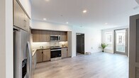 This single-floor, 3-bedroom, 2-bathroom residence offers a thoughtfully designed layout that maximizes functionality within a compact footprint. Light wood-look flooring runs throughout the unit, lending a cohesive, contemporary aesthetic to every room.

The kitchen is a standout feature, equipped with a full suite of stainless steel appliances—including a gas range, built-in microwave, dishwasher, and refrigerator. Warm wood-toned cabinetry extends to the ceiling, providing generous storage, while under-cabinet lighting illuminates the dark countertops. The kitchen opens toward the main living area, enhancing the sense of openness.

The primary bedroom is generously proportioned and connects to a dedicated closet, offering practical storage. The two secondary bedrooms are bright, clean spaces, one featuring a window with exterior views. All rooms are finished with crisp white walls and clean-lined gray interior doors.

Both bathrooms are finished with marble-style tile surrounds in the tub/shower combinations, complemented by chrome fixtures and light wood-look flooring. The overall design is clean and modern, with recessed lighting and a neutral palette maintaining a bright, airy ambiance throughout.