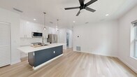 Located at 527 N Garden Ave in Clearwater, FL, this thoughtfully designed 3-bedroom, 2-bathroom unit offers a clean, modern aesthetic throughout. The open-concept kitchen and living area serves as the heart of the home, featuring white shaker cabinets, stainless steel appliances, a bold navy kitchen island with quartz countertops, globe pendant lighting, and a ceiling fan — all set atop light-toned wide-plank hardwood flooring that flows seamlessly through the entire space.

Each bedroom is bright and airy, equipped with ceiling fans and generous closet space, including louvered bi-fold closet doors in the primary bedroom. Two of the bedrooms provide direct access to private balconies with outdoor views of surrounding greenery, offering a refreshing indoor-outdoor connection.

Both bathrooms are finished with floor-to-ceiling marble-look tile, dark navy vanities, and brushed gold or chrome hardware. One bathroom features a frameless glass walk-in shower, while the other showcases a sleek, open wet-room layout. Additional conveniences include a dedicated laundry area, hallway, and two closets. The unit's crisp white walls, recessed lighting, and consistent modern finishes create a bright, polished atmosphere throughout.
