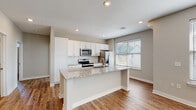 Located on Killian in Grand Rapids, MI 49525, this single-floor unit offers a thoughtfully designed open-concept layout with a seamless flow between the kitchen and living areas. The kitchen is a standout feature, showcasing crisp white cabinetry, granite countertops, a classic subway tile backsplash, and a full suite of stainless steel appliances including a range, over-the-range microwave, and refrigerator. A central island with a built-in sink provides additional prep space and casual seating. Warm hardwood-style flooring runs throughout the main living areas, complementing the neutral gray tones of the walls and creating a cohesive, modern aesthetic. The spacious living area is brightened by multiple windows with natural light and is equipped with a ceiling fan. Bedrooms feature plush carpeting and generously sized windows that invite in natural light. The bathrooms are finished with the same granite countertops and white cabinetry found in the kitchen, maintaining a consistent style throughout. One bathroom includes a tub/shower combination with tiled surround, while another offers a walk-in shower. Recessed lighting and clean white trim complete the polished, move-in-ready feel of this well-appointed space.