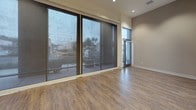 Located at 4440 Twain Ave in San Diego, Retail #102 is a single-level commercial space that combines modern design with versatile functionality. The main open area makes an immediate impression with its expansive floor-to-ceiling windows fitted with roller shades, allowing abundant natural light while maintaining privacy. Recessed lighting complements the natural light, and durable hardwood-style flooring runs throughout, adding warmth to the contemporary aesthetic. Elevated ceilings enhance the sense of openness, while a sleek frosted-glass sliding door provides stylish separation between areas.

The kitchen is well-appointed with white shaker cabinetry, light quartz countertops, a textured mosaic tile backsplash, and a full suite of stainless steel appliances including a range, microwave, dishwasher, and a side-by-side refrigerator with water and ice dispenser.

The space includes two bathrooms. The first is a full bathroom featuring a soaking tub with shower, extended vanity with ample storage, and a stacked in-unit washer and dryer. The second is an ADA-compliant restroom equipped with grab bars, an open-concept vanity, and generous floor space, ensuring accessibility throughout the unit.