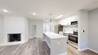 Located at 910 Rockefeller Dr in Sunnyvale, CA, this well-appointed 1-bedroom, 1-bathroom unit offers a thoughtfully designed single-level layout with modern finishes throughout. The open-concept kitchen and living area serves as the heart of the home, featuring a central island with a crisp white quartz countertop, white shaker-style cabinetry, stainless steel appliances including a refrigerator, range, microwave, and dishwasher, and a skylight that draws in abundant natural light. A stylish pendant light anchors the kitchen space, while durable wood-look luxury vinyl plank flooring extends across the main living areas. The living room is highlighted by a classic white brick fireplace, adding warmth and character to the space. The front entryway welcomes natural light through dual windows, creating a bright and open feel. The bedroom offers plush carpeting, a mirrored sliding closet, and a window overlooking the neighborhood. The clean, bright bathroom includes a full soaking tub and shower combo, wood-look flooring, and a conveniently located stacked washer and dryer unit. The overall aesthetic is fresh and modern, with a neutral gray and white palette throughout.