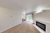 Located at 2445 S 222nd St in Des Moines, Washington, this single-floor, one-bedroom, one-bathroom unit offers a well-organized layout that makes efficient use of its compact footprint. The bright living room serves as the heart of the space, featuring plush carpeting, a white-surround fireplace with a sleek insert, a wall-mounted mini-split system for climate control, and a sliding glass door that opens directly to a private patio with green outdoor views. The combined kitchen and dining area is appointed with white cabinetry, light stone countertops, stainless steel appliances including a refrigerator and electric range, and wood-look vinyl flooring that carries through the entryway and hallway. The bedroom offers comfortable carpeting, a large window with a garden view, and a wide sliding-door closet for ample storage. The full bathroom includes a tub/shower combination with clean white surround and brushed nickel fixtures. A dedicated laundry area and an entrance closet add practical convenience. Neutral tones and clean finishes throughout lend the space a tidy, move-in-ready character.