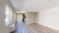 This single-story unit on Moorpark Street in Studio City, Los Angeles, presents a thoughtfully updated interior with a clean, neutral aesthetic throughout. The open living area is finished with light-toned wood-look flooring that extends seamlessly across the space, complemented by textured popcorn ceilings and warm beige walls. A ceiling fan provides added comfort, while a window allows natural light to filter in, enhancing the open feel of the room.

The kitchen is a standout feature, outfitted with sleek gray cabinetry offering generous storage both above and below the countertops. White quartz-style counters and a white subway tile backsplash provide a crisp contrast to the cabinetry. Stainless steel appliances, including a refrigerator, built-in wall oven, and gas cooktop, complete the functional and modern setup. A peninsula counter with an overhang serves as a convenient breakfast bar, connecting the kitchen to the living space.

The bedroom features a spacious closet with sliding doors, a window for natural light, and the same light wood-look flooring found throughout. An adjacent hallway includes additional built-in cabinetry for storage. The bathroom presents a white vanity with a dark countertop, a round undermount sink, brushed nickel fixtures, and a full mirror, alongside a shower-tub combination.
