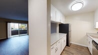 This single-floor residence offers a practical and cohesive layout with a blend of modern finishes and functional design. The open-concept kitchen serves as a central hub, featuring a peninsula countertop with light stone-style surfaces, white cabinetry with brushed nickel hardware, and stainless steel appliances including a refrigerator, range, and microwave. Under-cabinet lighting adds a polished touch, while the pass-through design connects the kitchen seamlessly to the adjacent living areas.

The living space is finished with rich, dark hardwood-style flooring that extends through the main areas, creating a warm and cohesive aesthetic. A sliding glass door opens to a private balcony, allowing natural light to flood the room and offering views of the surrounding neighborhood. Neutral warm-beige walls throughout provide a versatile backdrop.

The bedrooms are carpeted for added comfort and feature windows that bring in natural light. The bathroom is neatly appointed with a single vanity topped with a stone-style countertop, white cabinetry, a large mirror, and a well-lit sconce above. Clean white trim and consistent finishes tie the space together throughout, giving the residence a tidy, move-in-ready presentation.