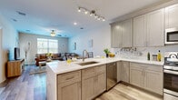 Located at 1-5 Soldier Hill Rd in Paramus, NJ, this thoughtfully designed single-floor residence offers a seamless open-concept layout with consistent light wood flooring throughout. The kitchen is a standout feature, equipped with taupe shaker-style cabinetry, gleaming white quartz countertops, a peninsula with an undermount sink, a decorative leaf-motif tile backsplash, and a full suite of stainless steel appliances including a gas range, built-in microwave, dishwasher, and refrigerator. A track lighting fixture provides ample task illumination. The kitchen flows naturally into the combined living and dining area, where a ceiling fan, large windows with horizontal blinds, and a sliding glass door invite natural light and provide access to a private balcony. The primary bedroom features a sliding door to a second balcony with outdoor views, while a second bedroom offers a bright, comfortable retreat with warm neutral tones and light wood flooring. The full bathroom is finished with dark espresso shaker vanity cabinetry, dual undermount sinks, white quartz countertops, a large mirror, and wood-look tile flooring. Multiple interior doors and closets, including a louvered utility closet, provide generous storage throughout the residence.