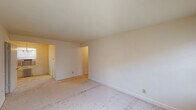 This single-floor residential unit offers a straightforward and functional layout, as visible in the dollhouse view. The living areas are finished with neutral-toned carpet flooring and cream-painted walls, creating a clean and understated aesthetic throughout. Windows in multiple rooms allow for natural light to filter in, contributing to a bright and airy feel.

The kitchen is equipped with a double-basin stainless steel sink, white laminate countertops, and wood-trimmed cabinetry offering ample storage both above and below the counter. The layout provides a practical workspace suitable for everyday use.

The bedrooms are generously proportioned, each featuring carpeted floors and individual closets with built-in shelving and hanging rods for organized storage. One bedroom includes a ceiling fan with integrated lighting, while radiator heating units positioned beneath the windows serve the living spaces, indicating a classic heating system.

The bathroom features a classic black-and-white mosaic tile floor, white wainscoting, and a window with blinds that provides natural light and ventilation. The space is clean and efficiently arranged.

Overall, this unit presents a functional and well-organized floor plan with consistent finishes throughout, offering a comfortable and livable environment with classic residential details.