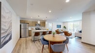 Located at 2305 Sokol Ct in Darien, Illinois, this well-appointed 2-bedroom, 2-bathroom single-floor residence offers a thoughtfully designed open-concept layout with modern finishes throughout. Light wood-look flooring flows seamlessly across the main living areas, creating a warm and cohesive aesthetic.

The heart of the home is a stylish kitchen featuring warm wood cabinetry with gold hardware, stainless steel appliances, a white quartz-topped island with bar seating, and globe pendant lighting. The kitchen opens directly to both the dining area and the living room, making the space ideal for entertaining. The living room is bathed in natural light from large sliding glass doors dressed with sheer vertical blinds.

The dining area accommodates a round wood table and sits adjacent to the entryway, providing an inviting transition into the home. The spacious primary bedroom features a ceiling fan, a large window, and direct access to its own bathroom. The bathrooms are finished with marble-look tile on both the floors and walls, including a soaking tub and shower combination. The second bedroom offers comparable comfort and natural light. A utility room and closet round out the functional layout of this well-designed Darien residence.