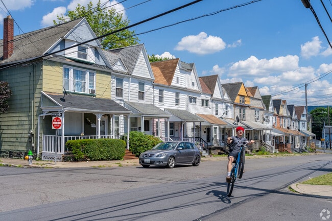 Wilkes-Barre townhomes stretch across bustling streets with youth and children riding bikes.