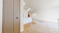 This two-floor residence offers a bright and functional layout with a clean, neutral aesthetic throughout. The main living area is generously proportioned, featuring vaulted ceilings that lend an airy, open feel, complemented by a ceiling fan and a skylight that draws in abundant natural light. Soft wall-to-wall carpeting extends across the living and bedroom spaces, creating a warm and comfortable atmosphere.

The kitchen is positioned adjacent to the living area and features an open pass-through counter with a raised breakfast bar, wood-accented cabinetry with white panel doors, light wood flooring, and standard appliances including an electric range and dishwasher. The layout promotes easy interaction between the kitchen and living spaces.

Sliding glass doors in the main living area provide access to the outdoors and allow natural light to fill the room, with views of surrounding greenery and mature trees visible from the exterior.

The bedroom is well-sized with carpeted flooring, vaulted ceilings, a ceiling fan, and direct access to a full bathroom. The bathroom is finished with a white vanity countertop, wood-accented cabinetry, a large mirror, and a combined tub and shower. Additional bedrooms feature carpeted flooring and windows dressed with vertical blinds. The overall ambiance of the space is clean, bright, and move-in ready.