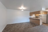 Located at 4528 S Triton Dr in Murray, Utah, this single-floor residence offers a practical and functional layout designed for comfortable everyday living. The open-concept living and dining area is finished with neutral-toned carpet and flows seamlessly into the kitchen, which features warm wood cabinetry, laminate countertops with a peninsula overhang, a stainless steel sink, tile flooring, and a skylight that draws in natural light. White appliances, including a refrigerator and dishwasher, are included. The living room is generously sized with sliding glass doors that open to a private balcony, offering outdoor views and additional natural light. Multiple bedrooms are carpeted and bright, each featuring windows with blinds that allow for natural light and privacy. Light wood-tone doors and double closets provide practical storage solutions throughout. The bathroom is well-appointed with tile flooring, a vanity with wood cabinetry, and a full tub and shower combination. Clean white walls and flush-mount lighting carry throughout the space, creating a consistent, understated aesthetic. The overall layout, as seen in the 3D floor plan, is compact yet well-organized, making efficient use of the available space.