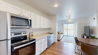 Located at 303 Airway Blvd in Bozeman, Montana, this well-appointed unit offers five bedrooms, two bathrooms, a dedicated office, and a living room across a single floor. The kitchen is outfitted with crisp white shaker cabinets, light countertops, and a full suite of stainless steel appliances including a range, microwave, and dishwasher. Warm hardwood-style flooring runs through the kitchen and living areas, creating a cohesive, inviting atmosphere. The living room is bathed in natural light and features a ceiling fan, a sliding glass door, and direct access to a private balcony that frames stunning views of the surrounding Montana landscape and mountain range. Each bedroom is finished with plush carpet, generous windows that capture the scenic outdoors, and a clean, neutral palette. The primary bedroom offers a comfortable, well-proportioned layout. Both bathrooms maintain a bright, functional design with white cabinetry, single-sink vanities, and shower-tub combinations. Connecting hallways provide smooth transitions between spaces, while the additional office room adds flexibility for work or study. Throughout the unit, white walls and abundant natural light contribute to an open, airy feel that complements the breathtaking Bozeman surroundings.