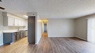 This single-floor, 2-bedroom, 2-bathroom unit offers a practical and comfortable layout with consistent wood-look flooring throughout. The open living and dining area is bright and spacious, highlighted by a sliding glass door with vertical blinds that provides natural light and access to an outdoor view. A central hallway connects the main living spaces to the private bedrooms, creating a clear and functional flow throughout the home.

The galley-style kitchen features two-tone cabinetry — white upper cabinets paired with charcoal lower cabinets — along with white countertops, a stainless steel sink, and stainless steel appliances including a refrigerator and range. Overhead lighting keeps the kitchen well-illuminated.

Both bedrooms are generously sized, each with neutral warm-toned walls, wood-look flooring, and windows fitted with horizontal blinds that frame outdoor greenery. The primary bedroom offers a dedicated closet with built-in shelving. A dedicated closet space with rod and shelf storage is also featured elsewhere in the unit.

The two bathrooms are clean and functional, each featuring a dark-toned vanity with white countertops, a large mirror, and wood-look flooring. One bathroom includes a full tub-shower combination. Textured ceilings are present throughout, and neutral warm beige tones give the entire unit a cohesive, move-in-ready appearance.