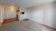 Located at 2102 E 51st St in Tulsa, Oklahoma, this single-floor unit offers a practical and functional layout designed for comfortable everyday living. The open living area is finished with neutral-toned carpet and light gray walls, creating a clean and versatile space. A ceiling fan overhead adds to the room's comfort, while a pass-through window connects the living area directly to the kitchen, enhancing the open feel between the two spaces.

The galley-style kitchen is well-appointed with warm honey-toned wood cabinetry, granite-look countertops, and a stainless steel sink. Black appliances, including a refrigerator and an electric range with overhead ventilation, complete the kitchen's functional setup. The kitchen features durable hardwood-style flooring that runs throughout, adding a consistent and polished look.

Additional rooms in the unit are generously sized, carpeted, and finished with the same neutral palette. One room benefits from a window fitted with blinds, allowing natural light to filter in, while another features a sliding glass door that brings in additional light. Textured ceilings are consistent throughout the unit, and each room is equipped with standard electrical outlets. The overall layout is straightforward and well-organized, offering a comfortable and move-in ready living environment.