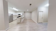 This contemporary single-story residence in Raleigh, NC offers 1,260 square feet of thoughtfully designed living space. The home boasts three bedrooms, including a generous 270 square foot primary suite, and two full bathrooms. The heart of the home is an open-concept living area, featuring a living room with a sleek fireplace and large windows that flood the space with natural light. The modern kitchen is equipped with stainless steel appliances, white cabinetry, and a hexagonal tile backsplash, complemented by a convenient center island. Light-toned wood-look flooring runs throughout the main living areas, while plush carpeting adds comfort to the bedrooms. Both bathrooms showcase clean lines with white vanities and shower/tub combinations. Additional amenities include a ceiling fan in the living room, window blinds for privacy, and a utility room for added convenience. The neutral color palette and contemporary finishes create a fresh, inviting atmosphere throughout this well-appointed home.