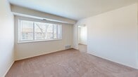 Located at 9200 Bustleton Ave in Philadelphia's 19115 zip code, this one-bedroom, one-bathroom residence offers a practical and comfortable single-floor layout. The space includes a variety of rooms: a living room, dining room, den, kitchen, bedroom, bathroom, utility room, three closets, and two hallways — providing functional versatility throughout.

The kitchen is well-appointed with rich warm-toned wood cabinetry, granite-style countertops, and black appliances including a gas range, refrigerator, and dishwasher, all set on light hardwood-style flooring. An interior pass-through window connects the kitchen to the dining area, enhancing the open feel between rooms.

The living and bedroom areas feature plush wall-to-wall carpeting and neutral walls that create a calm, inviting ambiance. The bedroom receives natural light through a wide window with views of the surrounding neighborhood. The space is generously sized and connects to the hallway through a private door.

Storage is well covered with three closets, including a carpeted walk-in style closet outfitted with built-in shelving and hanging rods. The bathroom includes a full tub/shower combination with tiled surround. The overall layout flows efficiently through connecting hallways, making this a well-organized and livable residence.