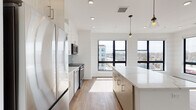 Located in Weymouth, MA, this modern single-floor residence showcases a thoughtfully designed open-concept layout with clean lines and contemporary finishes. The kitchen is a standout feature, offering sleek two-tone cabinetry in white and light wood, quartz countertops, a subway tile backsplash, and a full suite of stainless steel appliances including a refrigerator, range, microwave, and dishwasher. A central island provides additional prep and seating space, while pendant lighting adds a refined touch. Large, black-framed windows flood the kitchen and living area with natural light and offer views of the surrounding Weymouth neighborhood. Warm wood-tone luxury vinyl plank flooring runs throughout the living spaces and bedrooms, lending a cohesive and modern aesthetic. The bedrooms are bright and well-proportioned, each benefiting from generous window placement that frames outdoor views. The bathrooms are finished with large-format tile flooring, wood-toned vanities with quartz countertops, and clean white walls. The primary bathroom includes a soaking tub with tiled surround, while the secondary bathroom features a well-lit vanity with a framed mirror. Recessed lighting throughout ensures a bright and inviting atmosphere across the entire space.