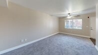 Located at 3939 Cranford Ave in Riverside, CA, this unit offers a well-organized single-floor layout comprising three bedrooms, two bathrooms, a kitchen, and a hallway. The living areas are finished with soft gray carpeting throughout, complemented by warm beige walls and clean white baseboards that create a neutral, move-in-ready aesthetic. A ceiling fan with a light fixture is installed in the main living area, which also features a window that allows natural light to fill the space. The spacious primary bedroom is a standout feature, offering a sliding glass door that opens directly to a private balcony with outdoor views of surrounding greenery and a pool area, along with a sliding double-door closet for ample storage. Additional bedrooms also feature carpeted flooring and windows that invite natural light. The kitchen is fitted with white cabinetry, light speckled countertops, a double-basin sink, and wood-look vinyl flooring, providing a clean and functional cooking space with a skylight overhead. The two bathrooms include updated vanities with light stone-style countertops, large mirrors with overhead lighting, and wood-look flooring. One bathroom features a glass-door walk-in shower with chrome fixtures, adding a polished touch to the space.