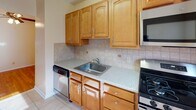 Unit #6 at 1139–1147 Pompton Ave in Cedar Grove, NJ is a well-maintained one-bedroom, one-bathroom residence offering a functional and comfortable single-floor layout. The living area is bright and open, featuring warm hardwood floors that run throughout and large windows that invite generous natural light, creating an airy and welcoming atmosphere. A ceiling fan adds comfort to the main living space, which also includes a wall-mounted air conditioning unit and baseboard heating for year-round climate control. The bedroom is a well-proportioned room with multiple windows offering views of the surrounding greenery, continuing the hardwood flooring and baseboard heating found throughout the unit. The kitchen is efficiently designed with warm honey-toned cabinetry, light stone-look countertops, a tiled backsplash, and stainless steel appliances including a gas range, built-in microwave, and dishwasher, alongside tile flooring. The bathroom features classic white subway-style wall tiles accented by a gray tile border, a soaking tub, and a window that provides natural ventilation and light. Overall, this unit offers a clean, practical, and bright living environment in a residential Cedar Grove location.
