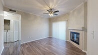 This single-story, one-bedroom, one-bathroom unit offers a thoughtfully organized layout across a comfortable footprint. The living room serves as the central gathering space, featuring wood-style laminate flooring, crown molding, a ceiling fan with light fixture, and a tile-surround fireplace with glass doors. Vertical blinds cover a sliding glass door, allowing natural light to filter in. The kitchen is efficiently designed with dark espresso cabinetry, stainless steel appliances including a refrigerator, range, and over-the-range microwave, along with a undermount sink and light-toned countertops. Wood-style flooring continues throughout this space. The bedroom offers plush carpet, a window for natural light, and direct access to a spacious walk-in closet equipped with wire shelving. The full bathroom includes a tiled tub-shower combination with sliding glass doors, a dark-cabineted vanity with a white countertop, and wood-style flooring. A hallway connects the primary living areas. The attached garage provides generous enclosed parking and additional storage potential, featuring an automatic opener and drywall-finished walls.