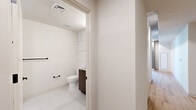 Located in the heart of Phoenix, this thoughtfully designed unit at 50 E Fillmore St offers a modern urban living experience with clean lines and contemporary finishes. The open-concept kitchen and living area serves as the heart of the space, featuring light wood-style flooring, exposed concrete ceilings with recessed lighting, and a pendant globe light that adds a warm, industrial-chic aesthetic. The kitchen is well-appointed with stainless steel appliances — including a full-size refrigerator, range, microwave, and dishwasher — complemented by white cabinetry, stone-tone countertops, and a matte black faucet. A sliding glass door opens from the living area onto a private balcony, offering views of the surrounding cityscape and filling the space with natural light. The bathroom is finished with floor-to-ceiling white subway tile, a floating walnut-toned vanity with stone countertop, an undermount sink, and matte black fixtures and hardware. A dedicated walk-in closet provides organized storage with adjustable shelving and hanging rods. The in-unit laundry room houses a stacked front-loading washer and dryer, adding everyday convenience to this well-planned urban residence.