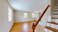 Located at 1160 Whitney Ave in Hamden, CT, this 2-bedroom, 1-bathroom home spans three floors, offering a well-organized and functional layout. Warm-toned hardwood flooring flows consistently throughout the main and upper levels, lending the home a cohesive and inviting character. Each floor is thoughtfully sized, contributing to a practical and comfortable living arrangement.

The main level features two living areas, a kitchen, and a hallway connecting the spaces. The kitchen is outfitted with white raised-panel cabinetry, a decorative tile backsplash, light tile flooring, and white appliances including a gas range and refrigerator—presenting a clean, classic look. Natural light filters in through a window above the sink, brightening the space.

Upstairs, the two bedrooms are generously proportioned and bathed in natural light from multiple windows. The primary bedroom is notably spacious, featuring dual windows that overlook the surrounding neighborhood. The full bathroom includes white subway tile wainscoting, a mirrored medicine cabinet, a window for natural light, and tile flooring.

The lower level provides a utility and storage area with a painted concrete floor, whitewashed block walls, and staircase access—offering practical additional space. A classic wood-railed staircase connects the floors with clean, traditional detailing throughout.