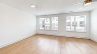 Located at 1100 Corinth St in Dallas, TX, this three-story home offers a well-organized layout across three distinct levels. The ground floor houses an attached garage equipped with an automatic opener, providing secure and convenient parking. The main living level sits above and features an open-concept design that integrates the living room, dining area, and kitchen into one cohesive space. The kitchen is outfitted with warm wood cabinetry, a white quartz island, stainless steel appliances, and large windows that invite generous natural light and outdoor views. Light hardwood flooring and clean white walls carry throughout this level, complemented by a ceiling fan in the living area. A private balcony off this floor extends the living space outdoors, offering views of the surrounding streetscape and landscaped greenery with warm wood railing accents. The upper floor is dedicated to the two bedrooms, each with plush carpeting, and supported by hallways connecting to the bathrooms and closets. The primary bedroom is a comfortable, well-proportioned retreat with its own closet featuring built-in shelving and hanging rods. Three full bathrooms are distributed across the home to serve all levels. Carpeted staircases with wood handrails connect all three floors, creating a smooth flow throughout this thoughtfully designed Dallas residence.