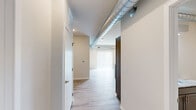 Located in Pleasant Hill, Iowa, this thoughtfully designed one-bedroom, one-bathroom unit offers a clean, contemporary aesthetic across a single floor. Light wood-look flooring runs throughout the entire space, lending a cohesive and airy feel, while exposed metallic ductwork adds an industrial design accent that runs from the main living area into the bedroom corridor.

The open-concept kitchen and living area serves as the heart of the unit. The kitchen features a granite-topped island with a stainless steel sink, gray shaker-style cabinetry, and a full suite of stainless steel appliances including a refrigerator, range, and over-the-range microwave. Recessed lighting illuminates the space, and vertical blinds on a large sliding door allow for natural light and outdoor access.

The bedroom is a comfortably sized retreat with a window fitted with horizontal blinds that brings in natural light. The exposed ductwork continues here, adding to the unit's industrial character.

The bathroom is clean and functional, featuring a full tub-shower combination with brushed nickel fixtures. A dedicated in-unit laundry room houses a full-size washer and dryer, providing added convenience. A hallway closet completes the practical layout of this well-appointed unit.