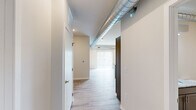 Located in Pleasant Hill, Iowa, this thoughtfully designed one-bedroom, one-bathroom unit offers a clean, contemporary aesthetic across a single floor. Light wood-look flooring runs throughout the entire space, lending a cohesive and airy feel, while exposed metallic ductwork adds an industrial design accent that runs from the main living area into the bedroom corridor.

The open-concept kitchen and living area serves as the heart of the unit. The kitchen features a granite-topped island with a stainless steel sink, gray shaker-style cabinetry, and a full suite of stainless steel appliances including a refrigerator, range, and over-the-range microwave. Recessed lighting illuminates the space, and vertical blinds on a large sliding door allow for natural light and outdoor access.

The bedroom is a comfortably sized retreat with a window fitted with horizontal blinds that brings in natural light. The exposed ductwork continues here, adding to the unit's industrial character.

The bathroom is clean and functional, featuring a full tub-shower combination with brushed nickel fixtures. A dedicated in-unit laundry room houses a full-size washer and dryer, providing added convenience. A hallway closet completes the practical layout of this well-appointed unit.