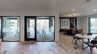 Located at 330 Westlake Ave in the Echo Park neighborhood of Los Angeles, this single-floor amenity space blends contemporary design with eclectic, artistic touches. The layout encompasses several distinct functional zones that flow seamlessly into one another across stone-tiled flooring throughout.

The lounge area serves as a central social hub, featuring rich velvet sofas in deep teal and warm cognac leather, layered over patterned area rugs. An ornate carved wood screen overhead adds a striking architectural accent, while a globe pendant light contributes ambient warmth. A wall-mounted television and moody dark walls give this zone an intimate, cozy character.

Two glass-enclosed conference rooms offer privacy without sacrificing visual openness. Framed in sleek black steel, these rooms are furnished with ergonomic seating and wood conference tables, and benefit from large windows that bring in natural light and outdoor greenery views. Curtain panels allow for additional privacy when needed.

A dedicated work lounge with built-in dark shelving, pendant lighting, and mixed seating provides a more informal collaborative setting. Adjacent to this is a kitchenette and café-style seating area branded "HiFi," featuring white subway tile, a wet bar, under-counter refrigeration, and marble bistro tables — ideal for casual gatherings or a quick break.