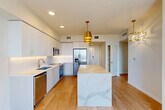 Located at 1532 S Federal Hwy in Boynton Beach, Florida, this thoughtfully designed one-bedroom, one-bathroom residence delivers a clean, contemporary aesthetic throughout its well-appointed single floor. The showpiece of the home is an expansive kitchen, anchored by a striking waterfall-edge quartz island that serves as both a functional workspace and a visual focal point. Crisp white shaker cabinetry reaches toward the ceiling, complemented by a classic subway tile backsplash, under-cabinet lighting, and a full suite of stainless steel appliances including a built-in wall oven, microwave, dishwasher, and French door refrigerator. Gold-toned pendant lighting adds a warm, sophisticated contrast to the bright, light-filled space. Light wood-look flooring flows through the main living areas, while the bedroom features plush carpet underfoot and a floor-to-ceiling window that frames sweeping views of the surrounding Boynton Beach landscape. The bedroom connects to a generously sized walk-in closet outfitted with wire shelving. The bathroom is finished with clean white subway tile surrounding a soaking tub and shower combination. A dedicated laundry area houses a stacked full-size washer and dryer, adding everyday convenience to this polished, move-in-ready residence.