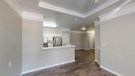 Located at 3939 E Trinity Mills Rd in Dallas, TX, this one-bedroom, one-bathroom residence offers a well-designed single-story layout with a cohesive blend of modern finishes and classic architectural details. The open-concept living, dining, and kitchen area serves as the heart of the home, anchored by rich dark hardwood-style flooring and crisp white crown molding throughout. Elegant wainscoting in the dining area adds a refined touch to the neutral, warm-toned palette.

The kitchen features a peninsula with a built-in sink and light countertops, white cabinetry, and a full suite of stainless steel appliances including a refrigerator, electric range, and dishwasher, along with an adjacent pantry for additional storage. The living area benefits from natural light streaming through large windows.

The bedroom is carpeted for comfort and includes double French doors leading to a spacious walk-in closet with wire shelving systems, providing generous storage. A second closet offers additional organization options.

The bathroom is well-appointed with an extended white vanity, dual sinks, a large framed mirror, and wood-style flooring. A dedicated laundry area and utility room add everyday convenience. The space is completed by a private patio, ideal for outdoor relaxation.