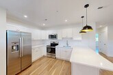 Located at 1 Pleasant St, Unit 305 in Cohasset, MA, this 2-bedroom, 1-bathroom unit offers a clean, modern aesthetic throughout. Warm-toned hardwood floors run continuously across all living areas, complementing the crisp white walls and trim that give the space a bright, fresh character.

The open kitchen and living area form the heart of the unit. The kitchen is outfitted with white shaker-style cabinetry, white countertops, and a full suite of stainless steel appliances including a side-by-side refrigerator with ice maker, an electric range, microwave, and sink. Recessed lighting illuminates the space, which flows seamlessly into the living area. A trio of windows lines one wall of the living room, filling it with natural light and offering views of the surrounding greenery.

The primary bedroom features angled architectural details, a built-in closet, and a natural light-filled window overlooking mature trees. The second bedroom is compact yet functional, with the same hardwood flooring and clean white finishes. The bathroom includes a full tub and shower combo with white tile surround and polished chrome fixtures. Throughout the unit, consistent finishes and thoughtful design create a cohesive, move-in-ready living environment.