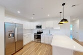Located at 1 Pleasant St, Unit 305 in Cohasset, MA, this 2-bedroom, 1-bathroom unit offers a clean, modern aesthetic throughout. Warm-toned hardwood floors run continuously across all living areas, complementing the crisp white walls and trim that give the space a bright, fresh character.

The open kitchen and living area form the heart of the unit. The kitchen is outfitted with white shaker-style cabinetry, white countertops, and a full suite of stainless steel appliances including a side-by-side refrigerator with ice maker, an electric range, microwave, and sink. Recessed lighting illuminates the space, which flows seamlessly into the living area. A trio of windows lines one wall of the living room, filling it with natural light and offering views of the surrounding greenery.

The primary bedroom features angled architectural details, a built-in closet, and a natural light-filled window overlooking mature trees. The second bedroom is compact yet functional, with the same hardwood flooring and clean white finishes. The bathroom includes a full tub and shower combo with white tile surround and polished chrome fixtures. Throughout the unit, consistent finishes and thoughtful design create a cohesive, move-in-ready living environment.