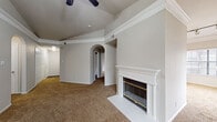 This single-floor residence offers a thoughtfully designed layout with a blend of comfort and functionality throughout. The spacious living room serves as the heart of the home, anchored by a classic white-mantled fireplace with a tile hearth and framed by soaring vaulted ceilings with a ceiling fan overhead. Large vertical-blind-covered sliding glass doors flood the space with natural light and provide outdoor access, while soft wall-to-wall carpet adds warmth underfoot. An elegant arched passageway connects the living area to the rest of the home, lending an architectural charm to the interior.

The kitchen is well-appointed with crisp white cabinetry, light granite-style countertops, and a full suite of stainless steel appliances including a refrigerator, range, microwave, and dishwasher. A central island provides additional prep and seating space, while hardwood-style flooring and track lighting complete the polished look.

The bedrooms are comfortably sized, each featuring plush carpet, ceiling fans, and windows with blinds that allow natural light to filter in. The bathrooms are clean and functional — one includes a soaking tub alongside a separate walk-in closet, while a second features a tub-shower combination with wood-look flooring. Together, these spaces offer a comfortable and well-maintained living environment.
