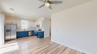 This efficiently laid-out 2-bedroom, 1-bathroom single-story home combines modern design with practical functionality throughout its thoughtfully organized floor plan. Light-toned luxury vinyl plank flooring flows consistently across all rooms, creating a cohesive and clean aesthetic.

The kitchen is a standout feature, showcasing bold two-tone cabinetry with rich navy blue lower cabinets paired with crisp white upper cabinets. A classic white subway tile backsplash and granite-look countertops complement the full suite of stainless steel appliances, including a refrigerator, range, microwave, and dishwasher. A sliding glass door off the kitchen/living area opens directly to a private backyard with a patio and green lawn, filling the space with abundant natural light.

The open living area benefits from a ceiling fan and seamless access to the outdoor space, enhancing both comfort and flow. Both bedrooms are well-proportioned, each equipped with a ceiling fan and natural light from windows with blinds. The primary bedroom includes a closet for ample storage.

The bathroom maintains the home's consistent design language, featuring navy blue cabinetry with granite countertops, wood-look flooring, and a window for natural ventilation. Hallways connect the rooms efficiently, completing this clean, move-in-ready home.