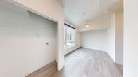 Located in the Hillman City neighborhood of Seattle, this efficiently designed studio unit offers a thoughtfully organized single-floor layout. Light-toned luxury vinyl plank flooring runs throughout the space, contributing to a clean, cohesive aesthetic.

The main living area features a ceiling fan with integrated lighting and a large window that allows natural light to fill the room and provides views of the surrounding neighborhood. A built-in open closet with a wire shelving system and hanging rod is conveniently integrated into the living space.

The kitchen is well-appointed with white cabinetry, open upper shelving, light-colored countertops, an under-cabinet range hood, a cooktop, a built-in microwave, and a full-size refrigerator. A stainless steel sink completes the setup, offering practical functionality in a compact footprint.

A hallway connects the living area to the bathroom, which features wood-look flooring, a wall-mounted toilet, grab bars, and a walk-in shower with a curtain rod—designed with accessibility in mind. The overall color palette is neutral and bright, with white walls and light finishes creating an open, airy ambiance throughout the unit.