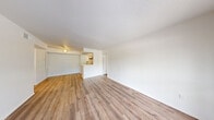 Located at The Nathaniel in Houston, TX, this two-bedroom, two-bathroom residence offers a well-organized, single-level layout designed for practical everyday living. Light-toned wood-look flooring flows consistently throughout the main living areas and bedrooms, creating a clean and cohesive aesthetic. The open living and dining area is bright and spacious, anchored by a ceiling fan and connected to the kitchen via a pass-through counter that enhances the open feel. A large sliding glass door and adjacent window in the living area allow generous natural light and provide views of outdoor greenery. The galley-style kitchen features white cabinetry, light stone-look countertops, a stainless steel sink, and black appliances including a range and refrigerator, all set on matching wood-look flooring. Both bedrooms are comfortably sized with white walls, ceiling fans, and windows that bring in natural light. The spacious primary bedroom includes a dedicated closet for ample storage. Each bathroom is finished with a white tub-shower combination, brushed gold fixtures, a white vanity, and tile flooring, maintaining a clean, consistent look throughout. Textured ceilings add subtle architectural character across the home.