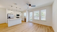 Located at 1601 Maguire Rd in Ocoee, Florida, this thoughtfully designed one-bedroom, one-bathroom residence offers a clean, contemporary aesthetic throughout its single-floor layout. Light hardwood-style flooring flows seamlessly across all main living areas, creating a bright and cohesive feel.

The open-concept kitchen and living room serve as the heart of the home. The kitchen is well-appointed with crisp white shaker cabinetry, a white quartz countertop island with pendant lighting overhead, stainless steel appliances including a French door refrigerator, electric range, built-in microwave, and dishwasher, complemented by a modern matte black faucet. Multiple windows allow natural light to pour in, with views to an outdoor balcony area.

The living area is open and airy, illuminated by a decorative chandelier and ceiling fan, with a clean white palette that enhances the sense of space. The bedroom is a comfortable size, featuring a ceiling fan, large windows with natural light, and direct access to both a closet and the hallway. The bathroom includes a full tub-shower combo with white tile surround, oil-rubbed bronze fixtures, a granite-topped vanity, and tile flooring. A dedicated laundry room with overhead wire shelving and a water heater completes the unit.