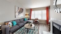 This single-story residence in Westminster, Colorado offers a well-organized floor plan that connects living, dining, kitchen, and sleeping areas in a cohesive layout. The living room is bright and welcoming, featuring vaulted ceilings, wood-style flooring, and large windows dressed with bold accent curtains that invite generous natural light. The space flows naturally toward a dedicated dining area, making it well-suited for both everyday living and entertaining.

The galley-style kitchen is outfitted with white cabinetry featuring modern hardware, light countertops, stainless steel appliances including a range and dishwasher, and a full-size refrigerator. Wood-style flooring continues throughout, and a window above the counter adds additional light.

The bedrooms are carpeted and comfortably sized, each featuring sliding glass doors with vertical blinds that open to outdoor views and allow sunlight to filter in. The primary bedroom includes access to a walk-in closet and an en-suite bathroom with dual sinks, white cabinetry, and a wide vanity mirror. A second full bathroom features a tub-shower combination with clean white tile surround and wood-style flooring.

Overall, the residence presents a neutral gray palette throughout, accented by modern fixtures, creating a clean, functional, and move-in-ready living environment.