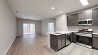 This well-appointed single-floor residence offers a thoughtfully designed open-concept layout that seamlessly connects the kitchen and living area. The kitchen is a standout feature, showcasing rich dark-toned cabinetry, a tiled backsplash, stainless steel appliances including a refrigerator, microwave, and gas range, and a peninsula with a white countertop and undermount sink — ideal for both meal preparation and casual dining. Light wood-style flooring flows throughout the main living areas, lending warmth and visual continuity to the space.

The living area is generously sized and bathed in natural light through a sliding glass door that opens to an outdoor area, complemented by vertical blinds for privacy. The bedrooms are comfortably proportioned, each featuring large windows that invite natural light and views of the surrounding exterior. The clean, neutral wall tones provide a versatile backdrop throughout.

Two bathrooms serve the residence: one features white tile flooring, a dark-cabineted vanity, and a well-lit mirror, while the other offers an extended vanity with ample drawer storage and dual mirrors. A dedicated in-unit laundry room with a full-size washer and dryer adds significant everyday convenience. Recessed lighting and modern fixtures complete the polished, contemporary aesthetic of this home.