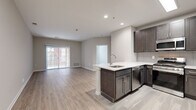 This well-appointed single-floor residence offers a thoughtfully designed open-concept layout that seamlessly connects the kitchen and living area. The kitchen is a standout feature, showcasing rich dark-toned cabinetry, a tiled backsplash, stainless steel appliances including a refrigerator, microwave, and gas range, and a peninsula with a white countertop and undermount sink — ideal for both meal preparation and casual dining. Light wood-style flooring flows throughout the main living areas, lending warmth and visual continuity to the space.

The living area is generously sized and bathed in natural light through a sliding glass door that opens to an outdoor area, complemented by vertical blinds for privacy. The bedrooms are comfortably proportioned, each featuring large windows that invite natural light and views of the surrounding exterior. The clean, neutral wall tones provide a versatile backdrop throughout.

Two bathrooms serve the residence: one features white tile flooring, a dark-cabineted vanity, and a well-lit mirror, while the other offers an extended vanity with ample drawer storage and dual mirrors. A dedicated in-unit laundry room with a full-size washer and dryer adds significant everyday convenience. Recessed lighting and modern fixtures complete the polished, contemporary aesthetic of this home.