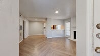 Located at 6000 Oakmont Trail in Fort Worth, TX, this one-bedroom, one-bathroom residence offers a well-designed single-floor layout. The open-concept living and kitchen area is immediately eye-catching, showcasing stylish herringbone-patterned light wood flooring that extends throughout the main living spaces. A white brick fireplace serves as the living room's focal point, flanked by windows fitted with blinds that allow for natural light control. The kitchen features white cabinetry, stainless steel appliances including a range, microwave, and refrigerator, complemented by a pass-through window that connects to the living area. A dedicated dining space flows naturally from the kitchen. The spacious bedroom is finished with plush carpet, ceiling fan, and ample natural light from multiple windows. It connects conveniently to a hallway with mirrored sliding closet doors and a full bathroom featuring white vanity cabinetry and generous counter space. An in-unit laundry area houses a full-size washer. Textured ceilings are present throughout, and neutral gray walls create a cohesive, modern palette. The layout also includes a dedicated hallway providing smooth connectivity between all rooms.