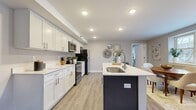 This single-floor, 2-bedroom, 2-bathroom residence offers a thoughtfully designed layout that balances functionality and modern style. The open-concept kitchen and living area serves as the heart of the home, featuring crisp white shaker cabinetry, quartz countertops, stainless steel appliances — including a refrigerator, electric range, and built-in microwave — and a dark-accented kitchen island with a single-basin sink. Light wood-tone flooring runs throughout the main living areas, complementing the neutral gray walls and recessed lighting overhead. The living room offers generous natural light through large windows and provides ample space for comfortable seating arrangements. Both bedrooms are carpeted and well-proportioned, with the primary bedroom featuring a dedicated closet with sliding doors. Each bedroom benefits from natural light via large windows. The two bathrooms are finished consistently, with shaker-style vanities, white countertops, wood-look flooring, and full tub-shower combinations with tiled surrounds. Two closets provide additional storage throughout the unit. The overall aesthetic is clean, contemporary, and move-in ready, with a cohesive neutral palette that lends itself to a variety of interior styles.